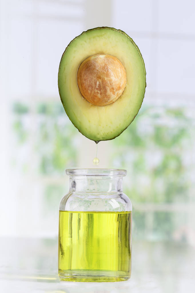 新鲜的鳄梨和油落在白色瓶子里Fresh avocado and oil falling in a bottle on white
