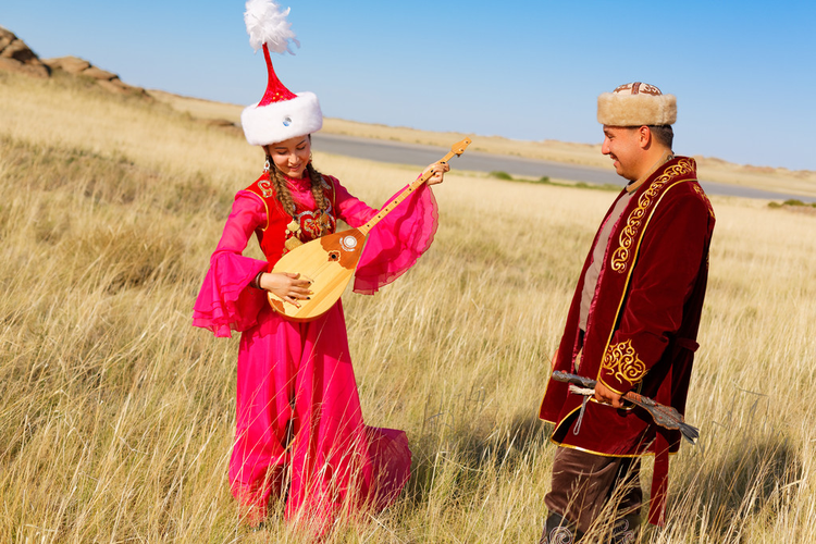 草原上身着民族服饰的哈萨克男女在演奏多比拉和跳舞Kazakh man and woman in national costumes in the steppe playing dombyra and dancing.jpeg