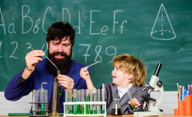 化学很有趣。在学校实验室学习化学。父亲和儿子在学校。科学家研究和实验回到学校。带小男孩的老师。生物学科学实验室
