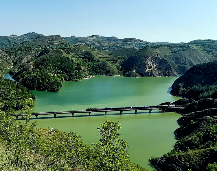宝鸡市唐河村远眺，陇海铁路穿山越水，贯通东西。初夏的唐河村，山青水绿，一声鸣笛，火车穿越山洞而出。
